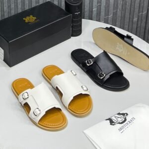 A pair of white and black double strap buckle sandals with silver buckles, accompanied by a black box and white cloth bag, showcasing the epitome of luxury footwear.