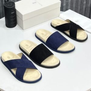 A stylish display of luxury suede slides in navy and black, accompanied by a white shoe box and dust bag, showcasing the perfect blend of comfort and elegance.