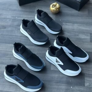 A collection of black leather sneakers with white soles and metallic accents arranged on a wooden floor, exuding luxury and style.