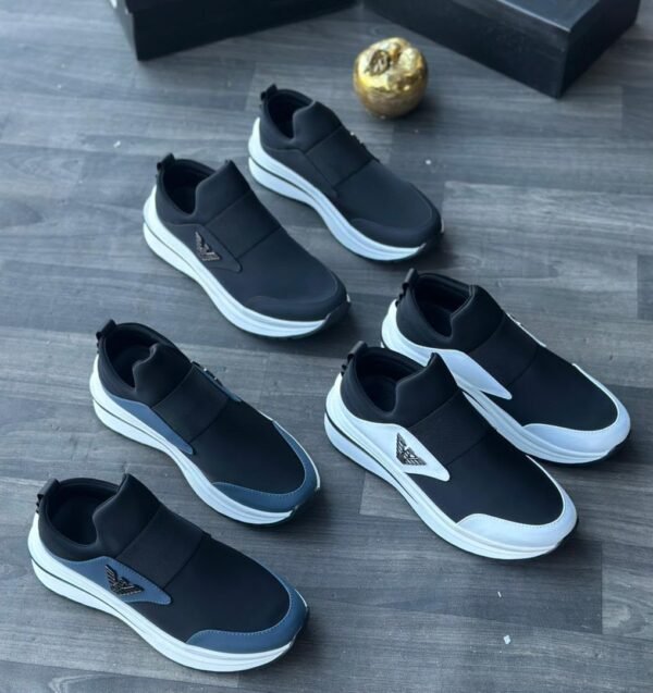 A collection of black leather sneakers with white soles and metallic accents arranged on a wooden floor, exuding luxury and style.
