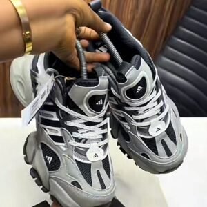 A pair of grey, black, and white Adidas Yung-96 sneakers being held by a hand, showcasing the shoe's sleek design and vibrant color scheme.