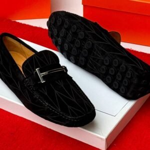 root A pair of luxurious navy blue loafers with a sleek design and distinctive black buttons on the soles, presented on a white shoe box against a vibrant red background.