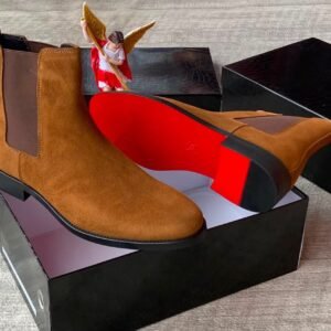 A pair of luxurious brown suede Chelsea boots with elastic sides, presented in an open black box with a red interior, exuding high-end quality and style.