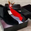 A pair of luxurious brown suede Chelsea boots with elastic sides, presented in an open black box with a red interior, exuding high-end quality and style.