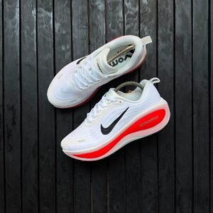 root A pair of white Nike sneakers with blue soles and black Nike swoosh logo, next to an orange Nike shoe box on a dark wooden background.