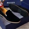 Luxury black suede loafers with tan soles and blue shoe boxes, exuding high-end style and sophistication.