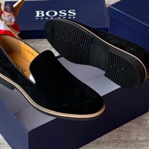 Luxury black suede loafers with tan soles and blue shoe boxes, exuding high-end style and sophistication.