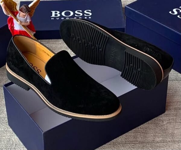 Luxury black suede loafers with tan soles and blue shoe boxes, exuding high-end style and sophistication.