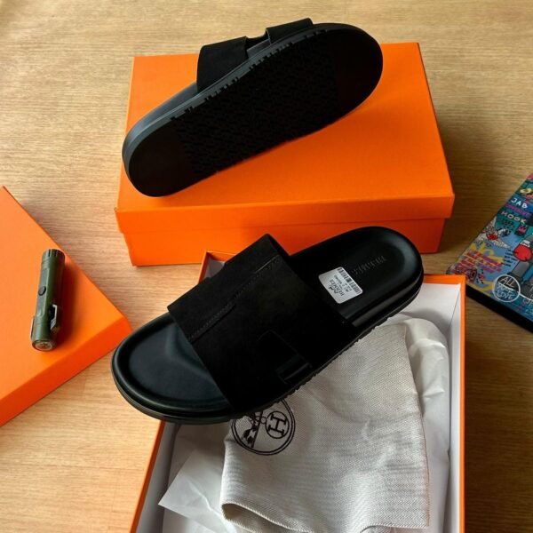 root Luxury black slide sandals in their orange box with packaging materials.