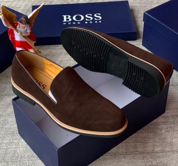 Luxury black suede loafers with tan soles and blue shoe boxes, exuding high-end style and sophistication.
