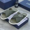 A pair of green Dior slides with white soles and CD logo on a navy blue shoe box.