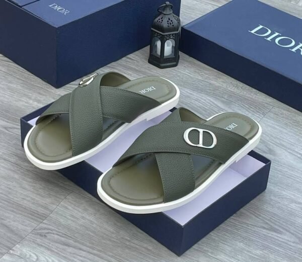 A pair of green Dior slides with white soles and CD logo on a navy blue shoe box.
