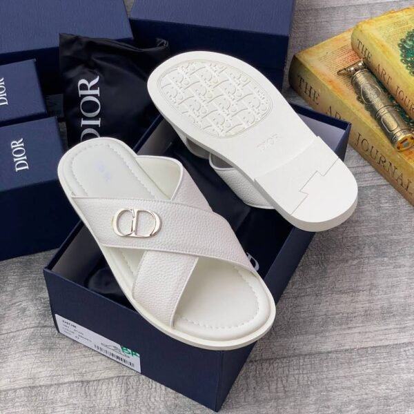 A pair of green Dior slides with white soles and CD logo on a navy blue shoe box.