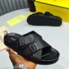 A hand holding a black Fendi slide with silver buckles, showcasing the luxurious design and attention to detail.
