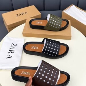 A pair of luxurious slides displayed on a pristine white table, accompanied by their elegant packaging and a dust bag, exuding an aura of high-end sophistication.