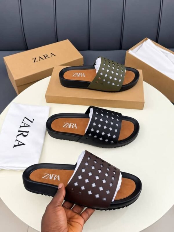 A pair of luxurious slides displayed on a pristine white table, accompanied by their elegant packaging and a dust bag, exuding an aura of high-end sophistication.