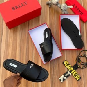 A pair of black Bally slides in their red boxes, exuding luxury and comfort, accompanied by a hand holding one of the slides.